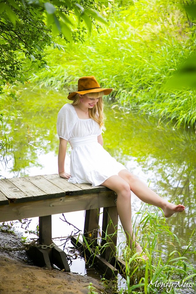 outside water deck grass trees greenery sunhat white dress senior littleton photography